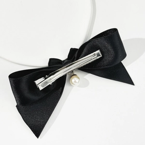 Detail of black silk bow hair clip with a hanging pearl and silver metal alligator clip
