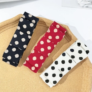 Detailed view of 3-piece polka dot bow hair clips in black, red, and white fabric