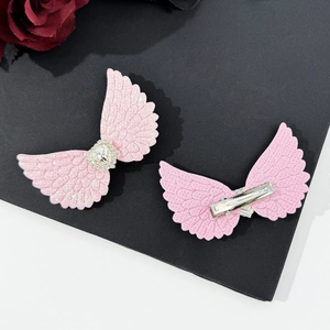 Detail view of pink angel wing hair clips with rhinestone hearts and alligator metal grips