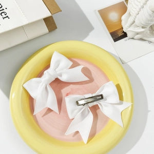 Detail of white satin ribbon bow hair clips with silver metal duckbill clip back