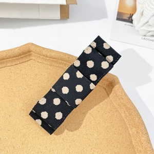 Detailed macro view of a vintage polka dot fabric hair clip on a premium wooden tray