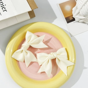 Close-up of cream white double-layered ribbon bow hair clips on a decorative tray