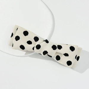 Detailed view of cream bow hair clip with black polka dots on ribbed grosgrain fabric