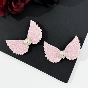 Close-up of pink sequined angel wing hair clips with heart-shaped crystal center