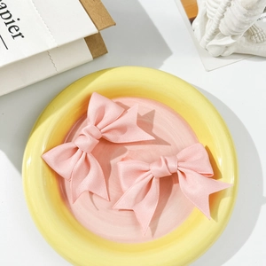 Detailed macro view of two sweet pink ribbon bow hair clips with textured satin fabric