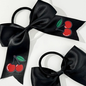 Detail of black silk satin hair ties with vibrant red cherry patterns and bow knots