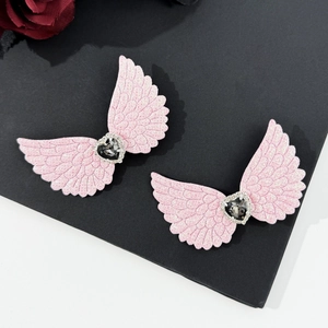 Detail view of two pink glitter angel wing hair clips with rhinestones on a black board