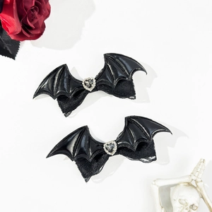 Detail of gothic bat wing hair clips with heart gemstone and lace on white backdrop