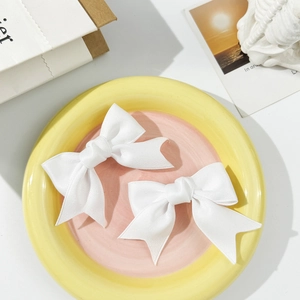 Detail of sweet white satin ribbon bow hair clips on a decorative ceramic tray