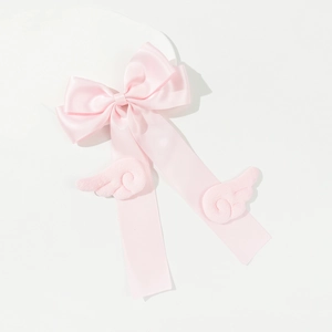 Detail einer rosa Satinschleife Haarklammer mit süßen Engelsflügeln und langen Bändern