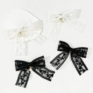 Detail view of fine lace bow hair clip with white pearl pendants in black and white