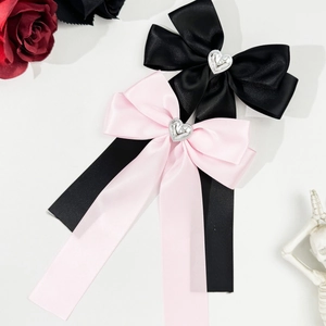 Détail de nœuds à cheveux en satin rose et noir avec des accents de cœur en argent