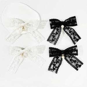 Detailed close-up of lace bow hair clips with pearls in elegant black and white colors
