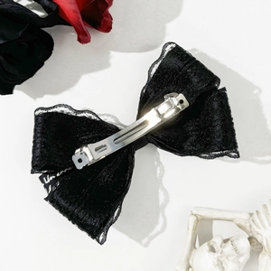 Macro detail of gothic black lace bow hair clip with silver metal spring clip back