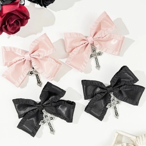 Detail of cross charms on pink and black satin bow hair clips in a gothic style