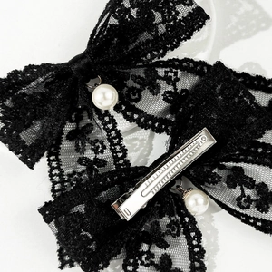 Macro detail of black lace bow hair clips with pearls and silver alligator metal grips