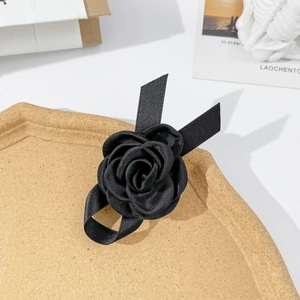 Gros plan d'une pince à cheveux rose en satin noir sur un plateau en bois texturé