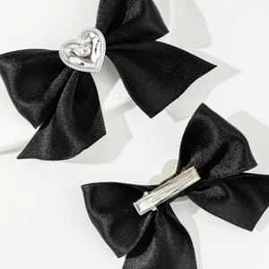Dettaglio di fermagli per capelli in raso nero con strass a cuore e clip a coccodrillo argento
