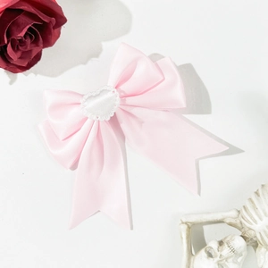 Pinza para el pelo con lazo de satén rosa y detalle de corazón en fondo blanco