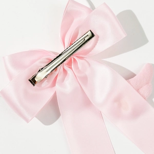 Süße rosa Haarspange mit Satinschleife und silberner Krokodilklemme auf Weiß