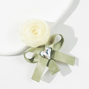 Detalle de pinza para pelo rosa de organza con lazo verde y cristal de corazón blanco
