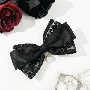 Detail view of black lace and satin bow hair clip featuring a white pearl pendant