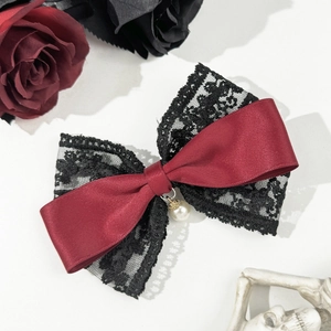 Macro detail of gothic burgundy satin and black lace bow hair clip with pearl pendant