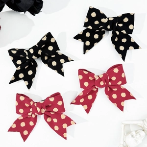 Close-up of polka dot bow hair clips in black and dark red with vintage gothic style