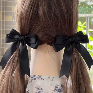 Detail of elegant black satin ribbon bow hair clips with long streamers on pigtails