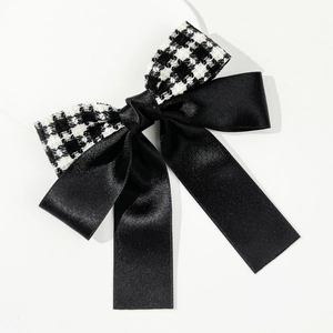 Detail of houndstooth and black satin bow hair clip with elegant long ribbons