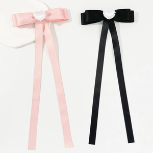 Close-up of pink and black satin bow hair clips with lace heart accents on white stones