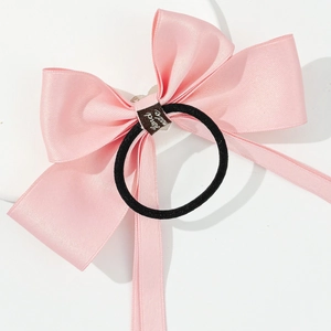 Close-up of pink satin bow hair tie with handmade label and high elasticity black band