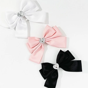 Detailaufnahme von Schleifen-Haarspangen aus Satin in Weiß, Rosa und Schwarz mit Herz-Schnalle