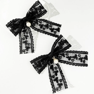 Pair of elegant black lace bow hair clips with pearls on a clean grey background