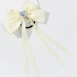 Elegant cream satin bow hair tie with silver heart charm and long ribbon streamers