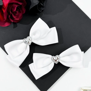 Détail de barrettes en satin blanc avec un centre en strass en forme de cœur