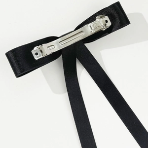 Detail view showing the back structure of a black satin bow hair clip with a silver metal clip