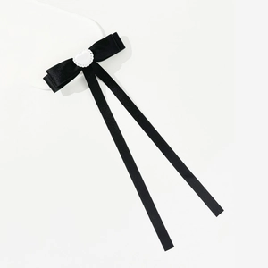 Detail of a black ballet style ribbon bow hairclip featuring a white heart center decoration