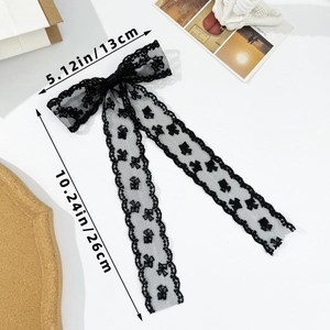 Detail view of black lace bow hair clip with floral patterns and long flowing ribbons