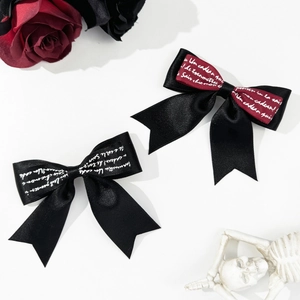 Close-up of gothic satin bow hair clip with French script print and metallic texture