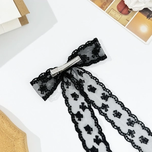 Elegant black lace bow hair clip with spade pattern on a clean white desk background