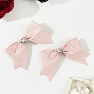 Elegante rosa Schleifen-Haarspangen mit Strass-Herzen auf weißem Hintergrund