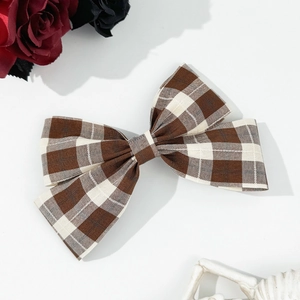 Detailed view of the brown plaid bow hair clip with dark academy style floral background