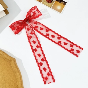 Elegant red lace bow hair clip with long ribbons on a minimalist aesthetic background