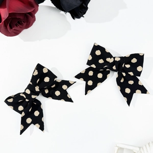 Set of two black polka dot bow hair clips with a vintage aesthetic on white background