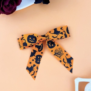 Close-up of Halloween orange bow hair clip with black pumpkin and witch patterns