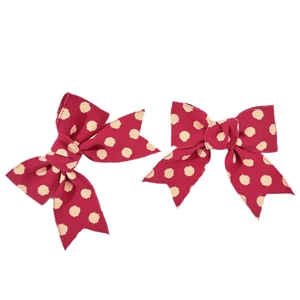 Pair of burgundy polka dot bow hair clips made of ribbed fabric on white background