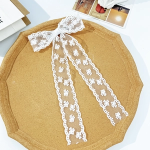 Close-up of white lace bow hair clip with long ribbons and delicate butterfly patterns