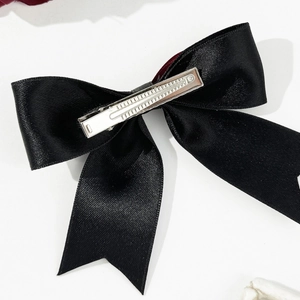 Detail view of the silver metal alligator clip on the back of a black satin bow hairclip