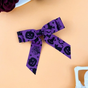 Detail of purple Halloween grosgrain bow with black cat and pumpkin patterns
